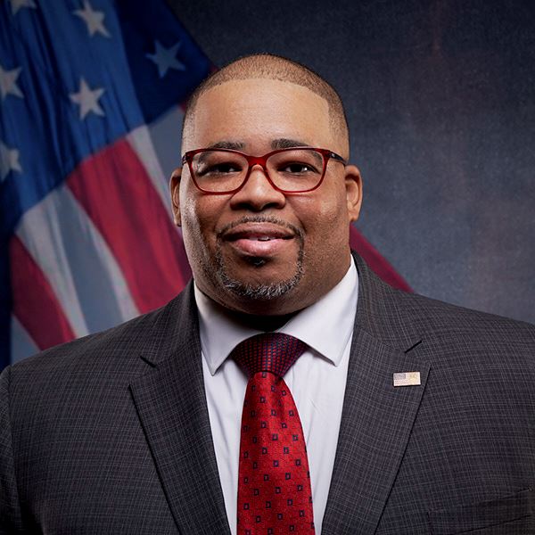 Black man in a suit in front of an American flag